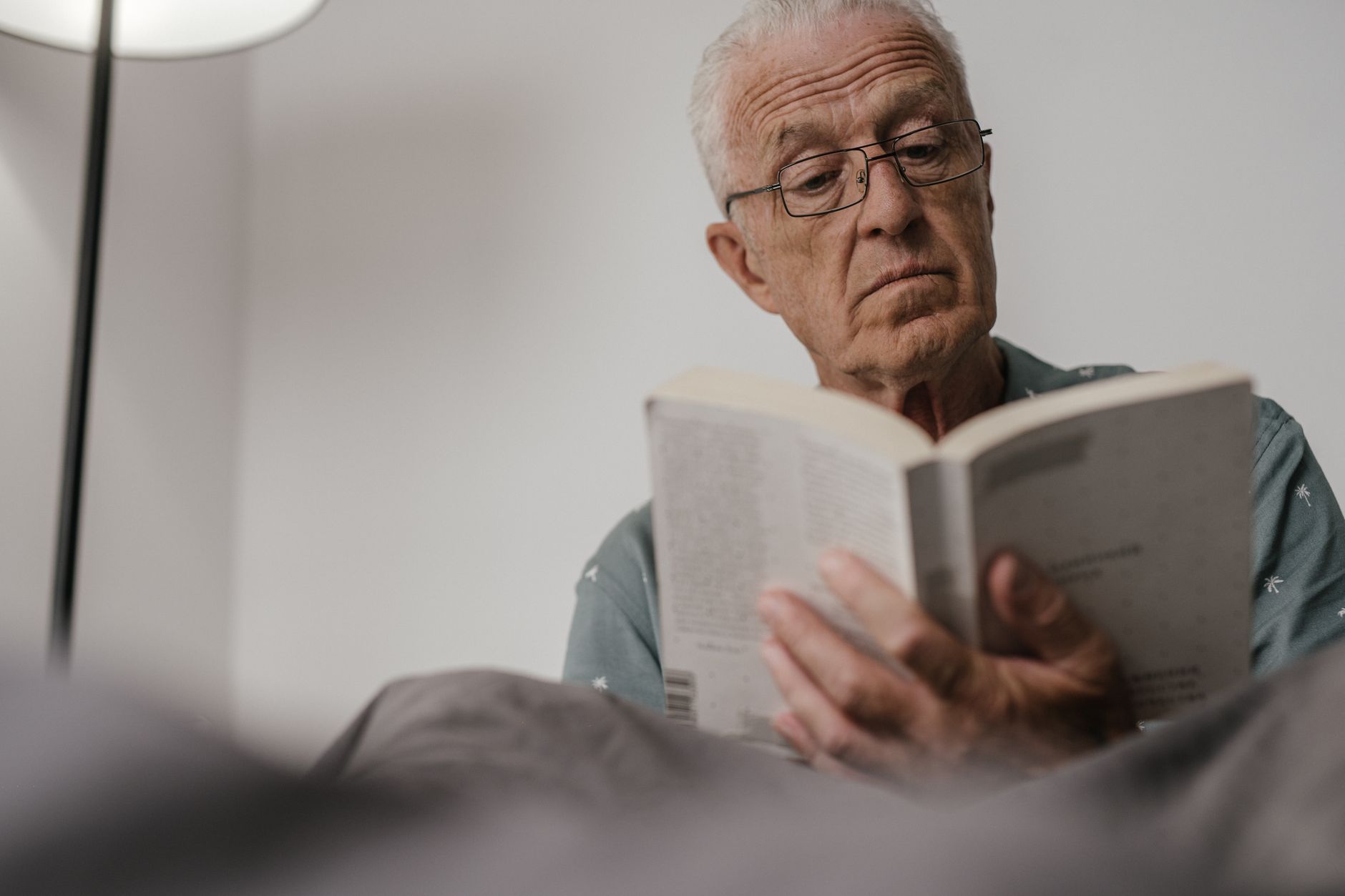 Augen im Alter – älterer Mann liest mit Brille ein Buch