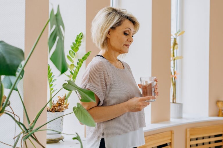 Hitze im Alter: Tipps für heiße Sommertage Hitze im Alter – ältere Frau trinkt ein Glas Wasser in einem hellen Raum
