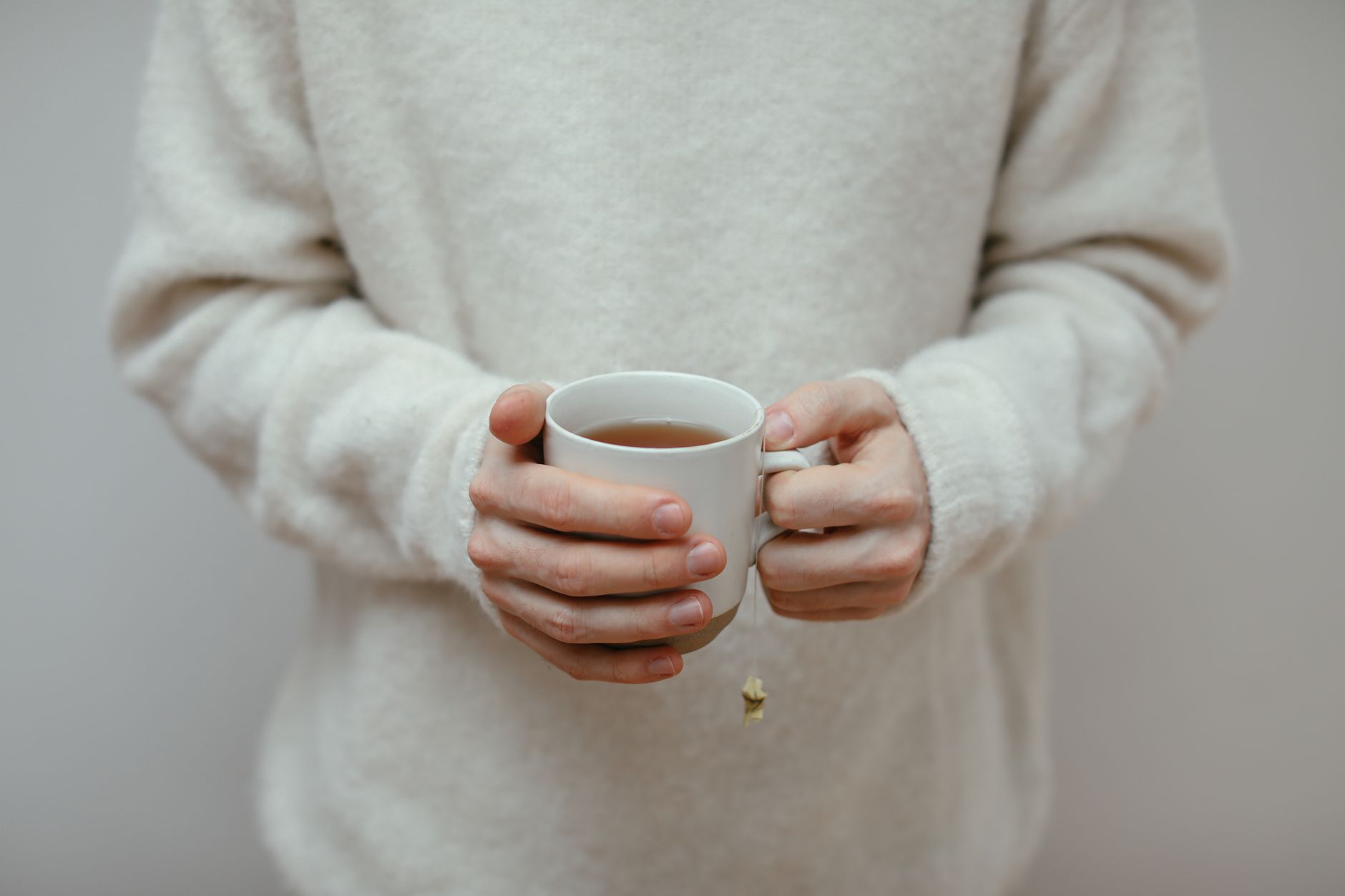 Kurze Genesungswünsche – Hände halten eine warme Tasse Tee