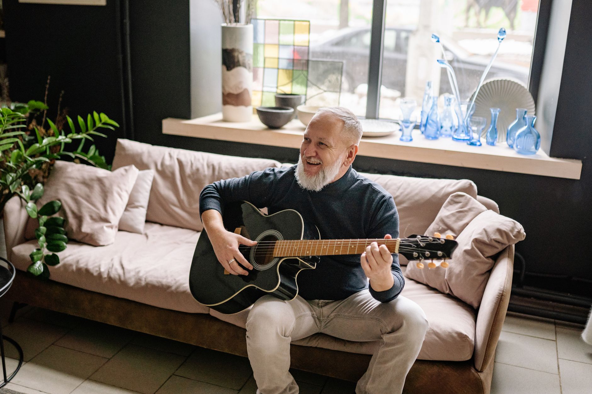 Musik im Alter – älterer Mann spielt fröhlich Gitarre
