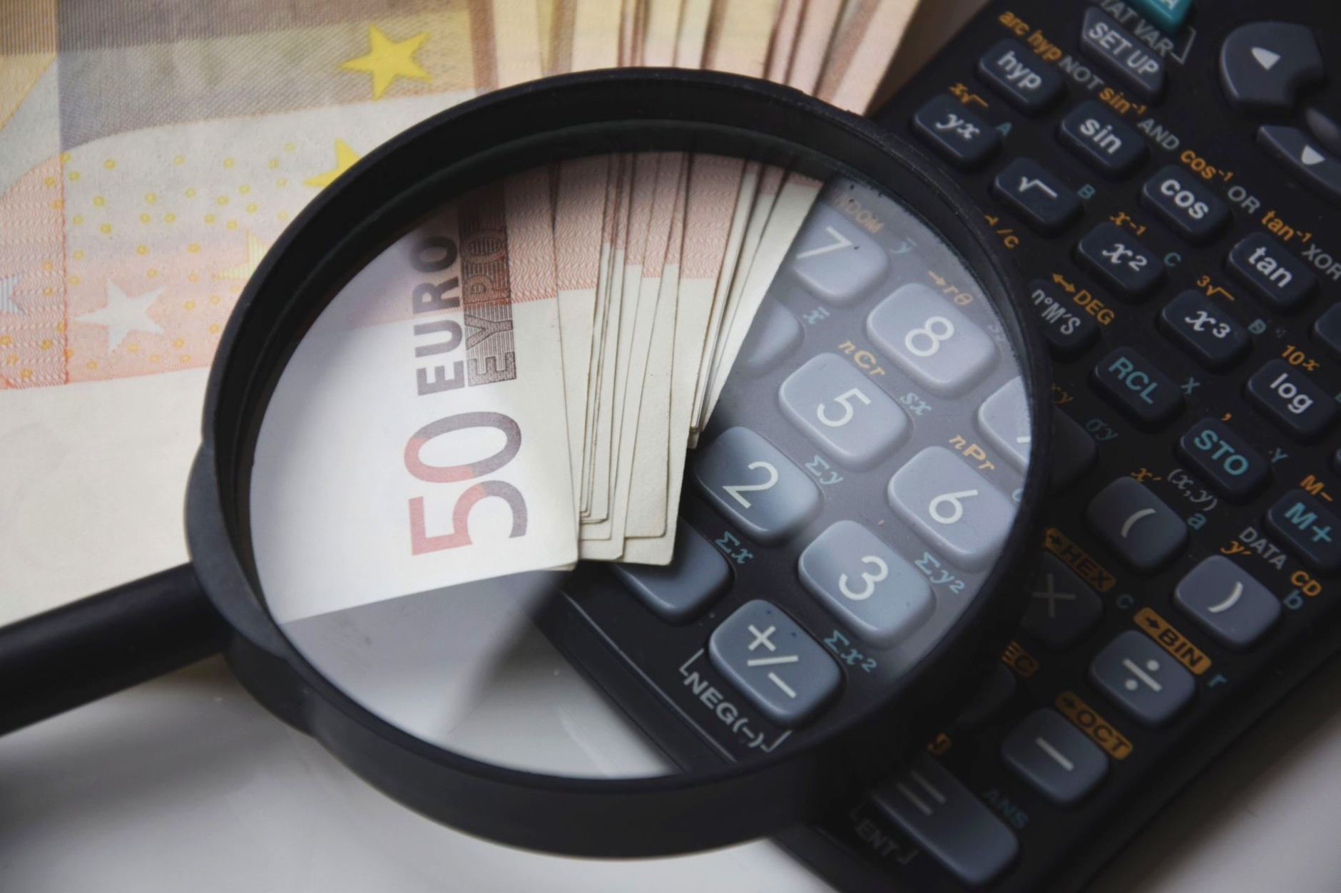 Pflegegeld steuerpflichtig – Euroscheine, Lupe und Taschenrechner