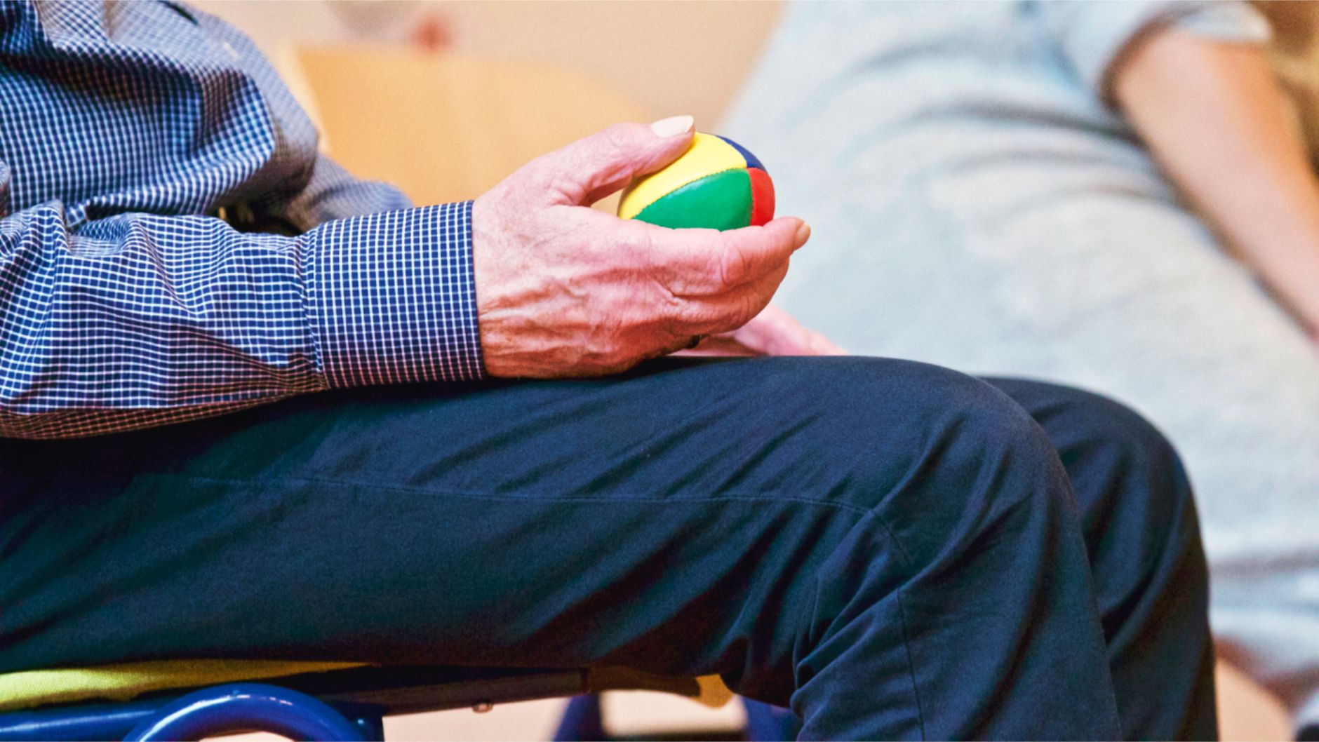 Stuhlgymnastik für Senioren – älterer Mann übt im Sitzen mit einem Therapieball