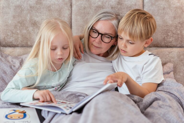 Vorlesen für die Enkel: Schöne Momente schaffen Vorlesen für die Enkel – Großmutter liest zwei Enkelkindern aus einem Buch vor
